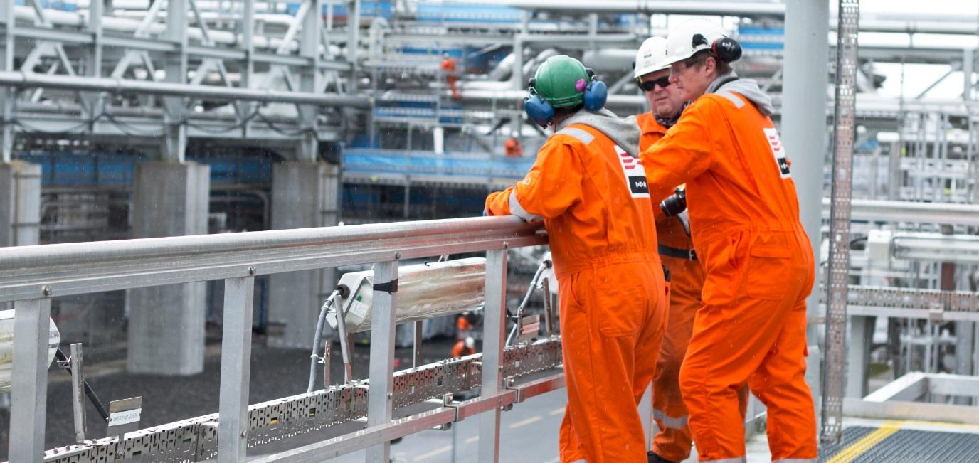 two men in orange work in a factory.