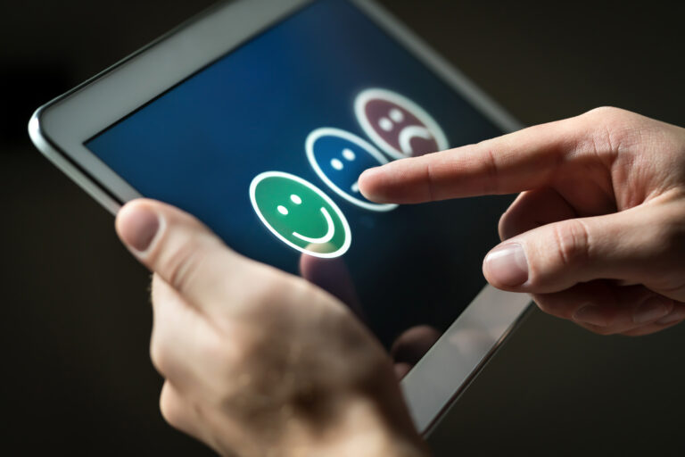 a person touching a tablet with a smiley face sticker on it.