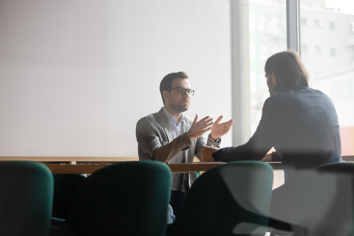 two people sitting at a table talking to each other.