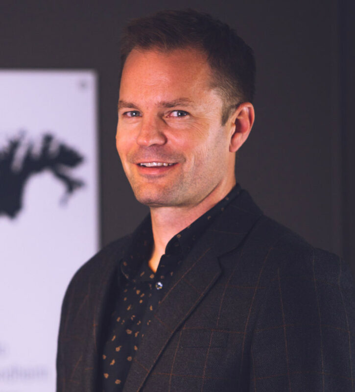 a man in a suit standing in front of a wall.