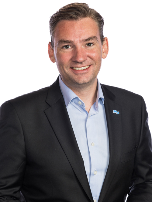 a man in a suit smiling for the camera.