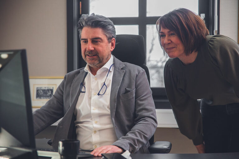 a man and a woman sitting at a desk in front of a computer.