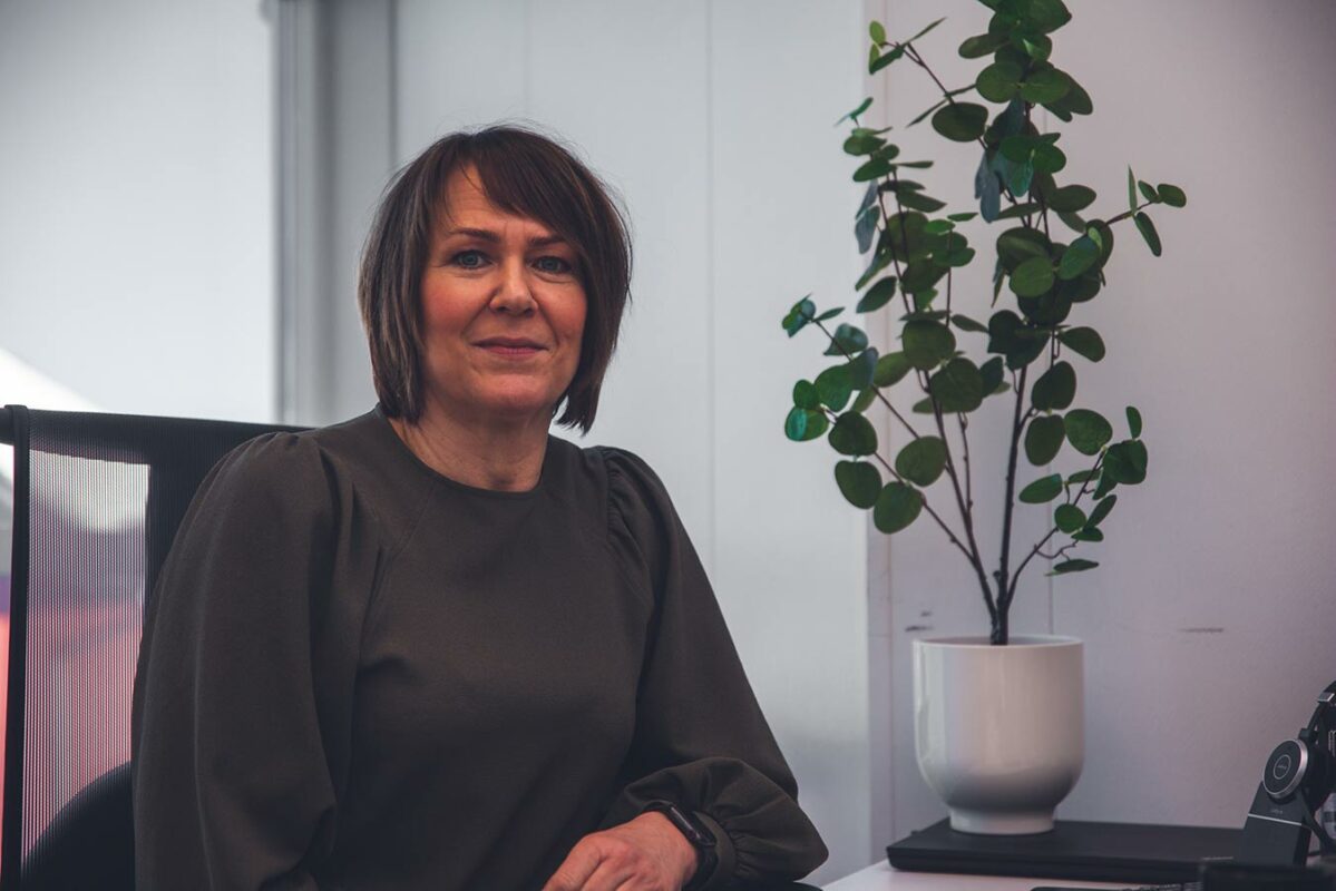 a woman sitting at a desk in front of a plant.