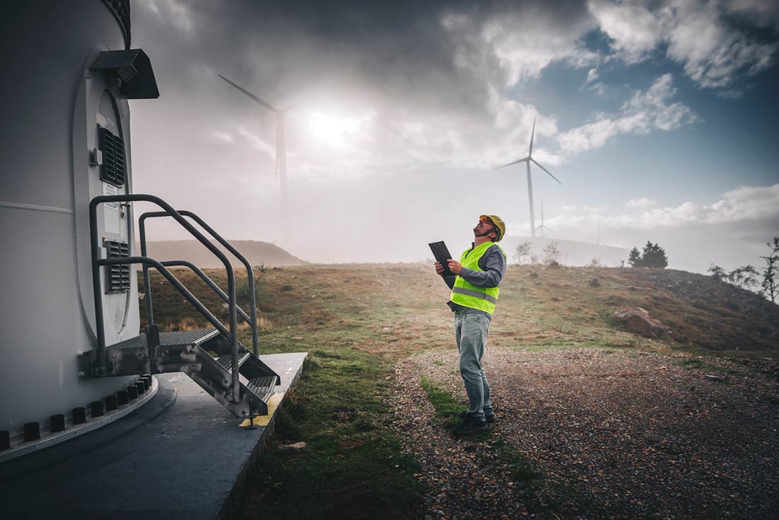 a man standing in front of a wind turbine.