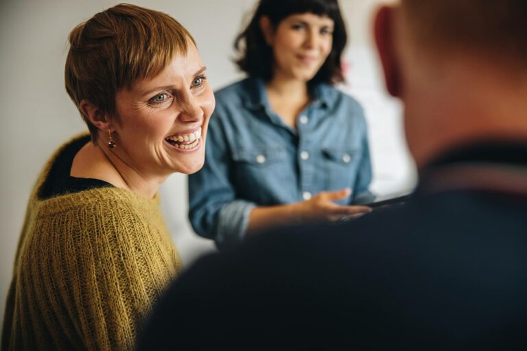 a woman smiling and talking to a man.