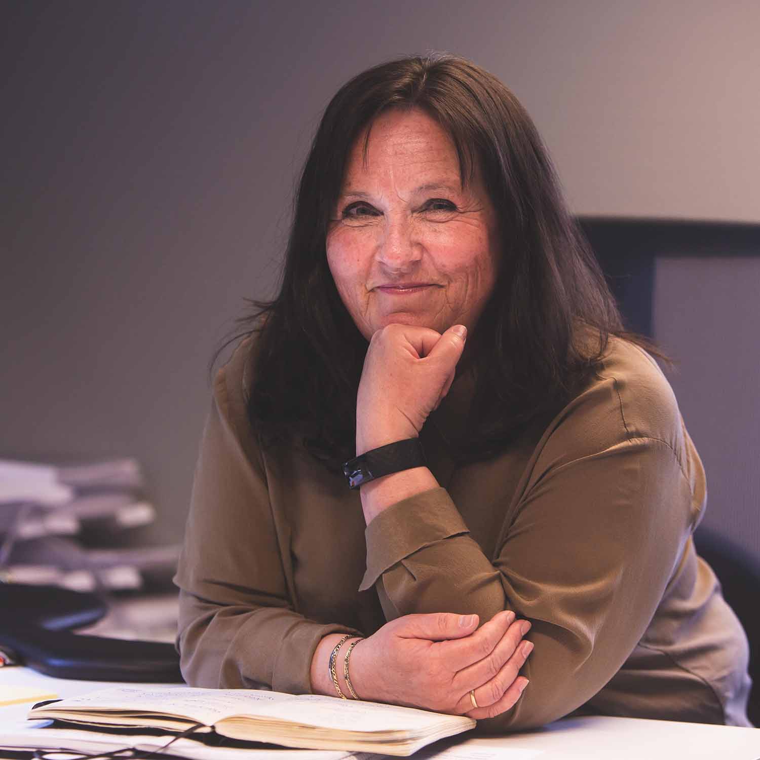 a woman sitting at a table with her hand on her chin.