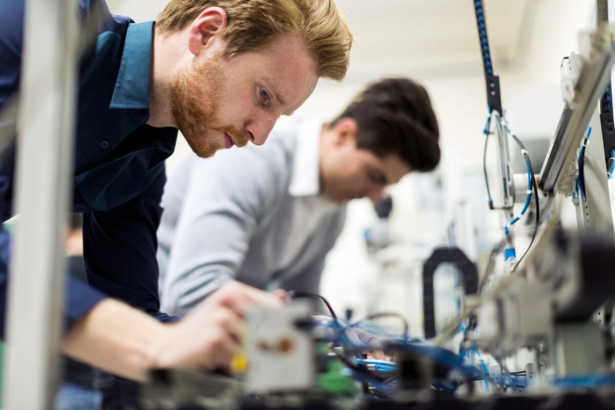 two men working on a machine in a factory.