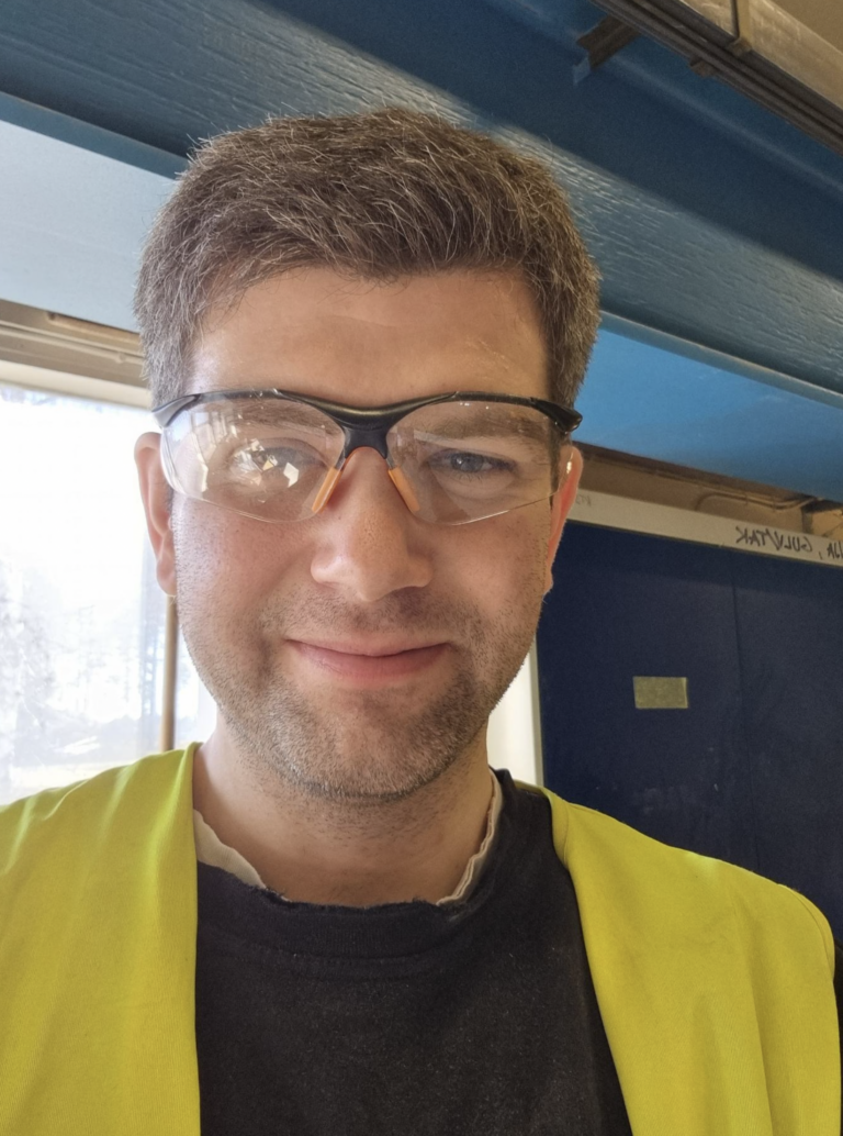 a man wearing glasses and a yellow vest.