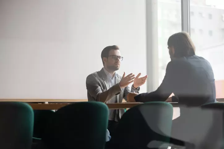 two people sitting at a table talking to each other.