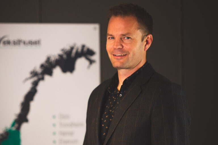 a man in a suit standing in front of a screen.