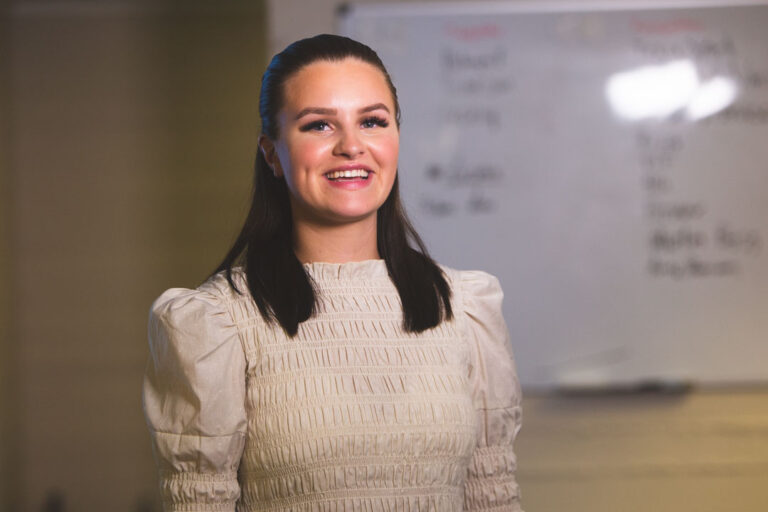 a woman standing in front of a white board.