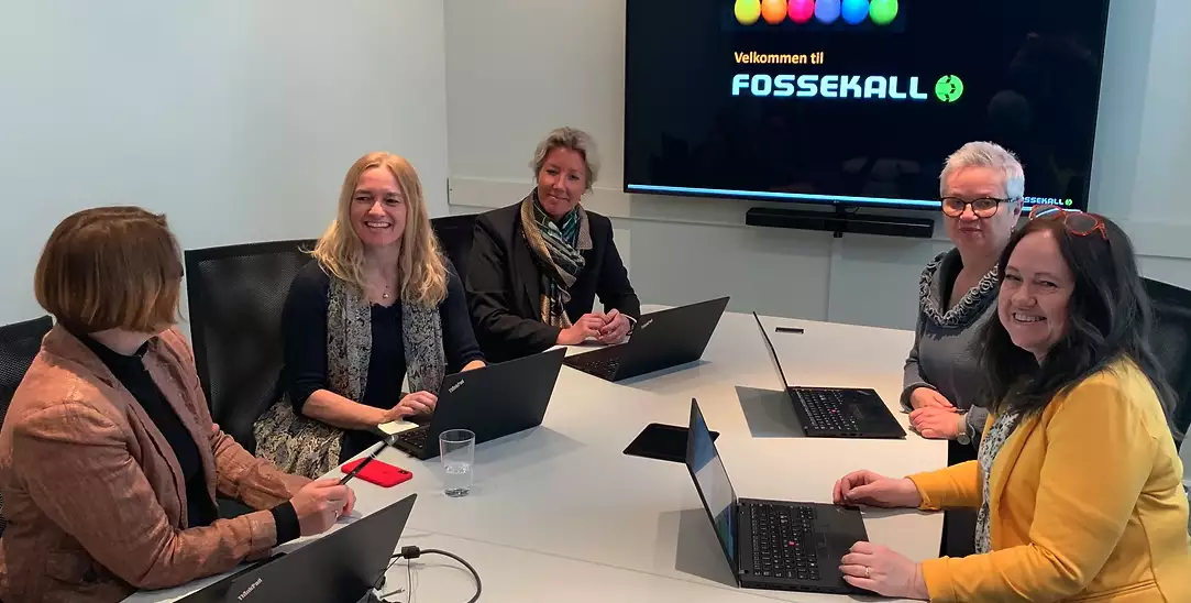 a group of people sitting around a table with laptops.