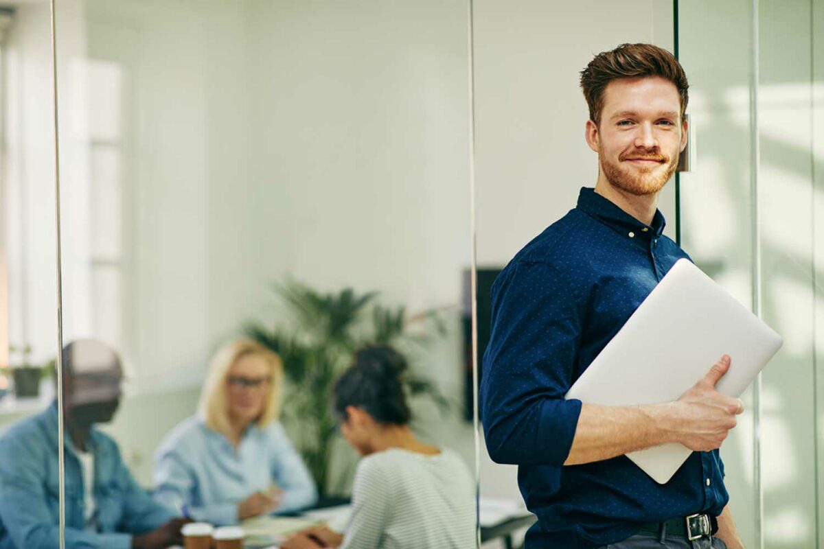 a man standing in an office holding a folder.