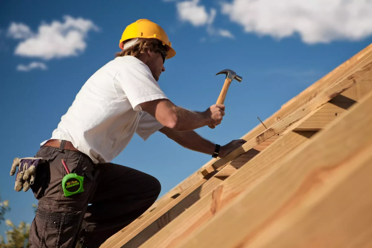 a man with a hammer on top of a roof.