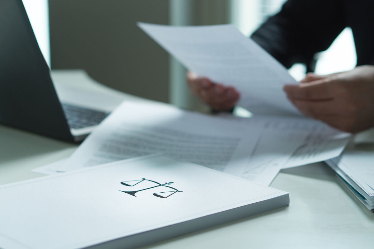 a person sitting at a desk with papers and a laptop.