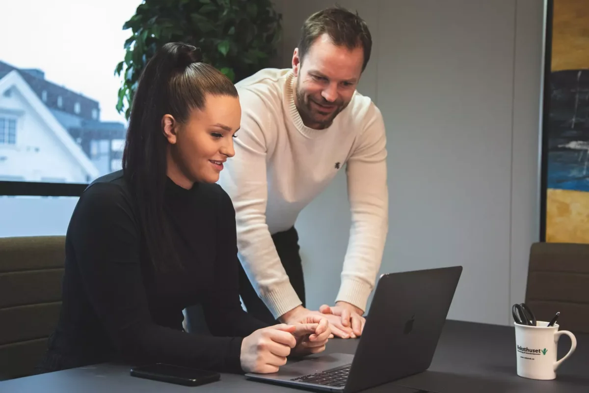 a man and a woman looking at a laptop.